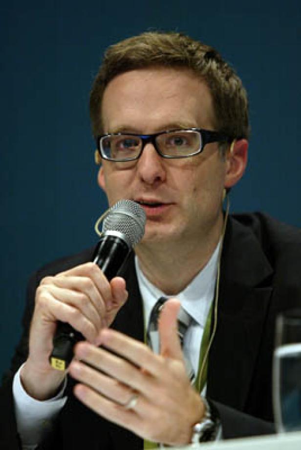 Ein Mann mit Brille spricht in ein Mikrofon.