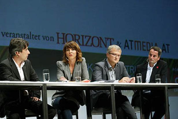 Vier Personen sitzen an einem Tisch während einer Podiumsdiskussion.