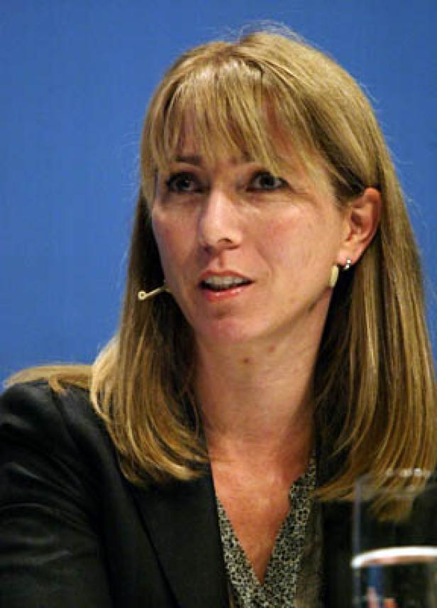 Eine Frau mit blonden Haaren spricht bei einer Konferenz.