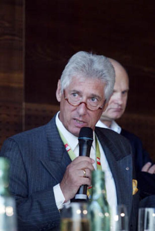 Ein Mann mit Brille und Anzug spricht in ein Mikrofon.