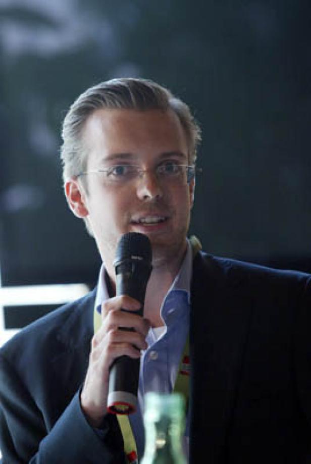 Ein Mann mit Brille hält ein Mikrofon und spricht.
