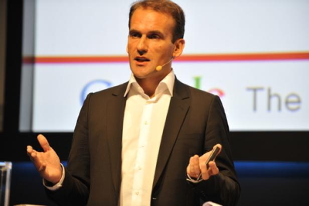 Ein Mann in einem Anzug hält eine Präsentation vor einer Leinwand mit dem Google-Logo.