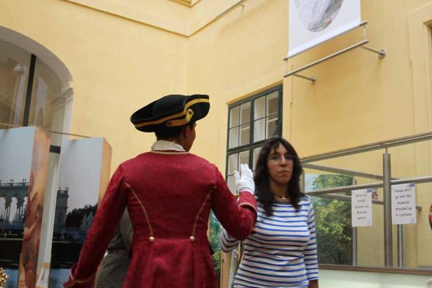 Ein Mann in historischer Kleidung steht neben einer Frau in einem Museum.