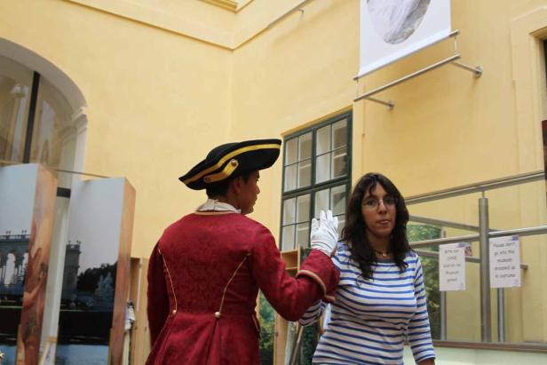 Eine Frau im gestreiften Oberteil steht neben einer Person im historischen Kostüm.