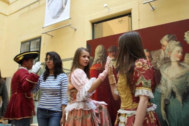 Eine Gruppe von Personen in Kostümen vor einem Gemälde.
