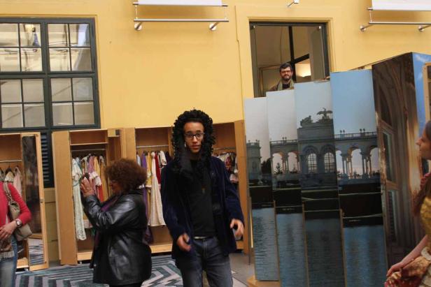 Ein junger Mann steht vor Kulissen mit Schloss Schönbrunn im Hintergrund.