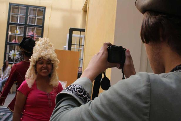 Eine Frau mit einer blonden Perücke wird von einer Person mit einer Kamera fotografiert.