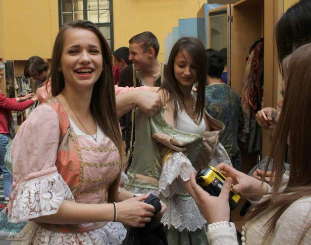 Junge Frauen wählen Kostüme in einer Garderobe aus.