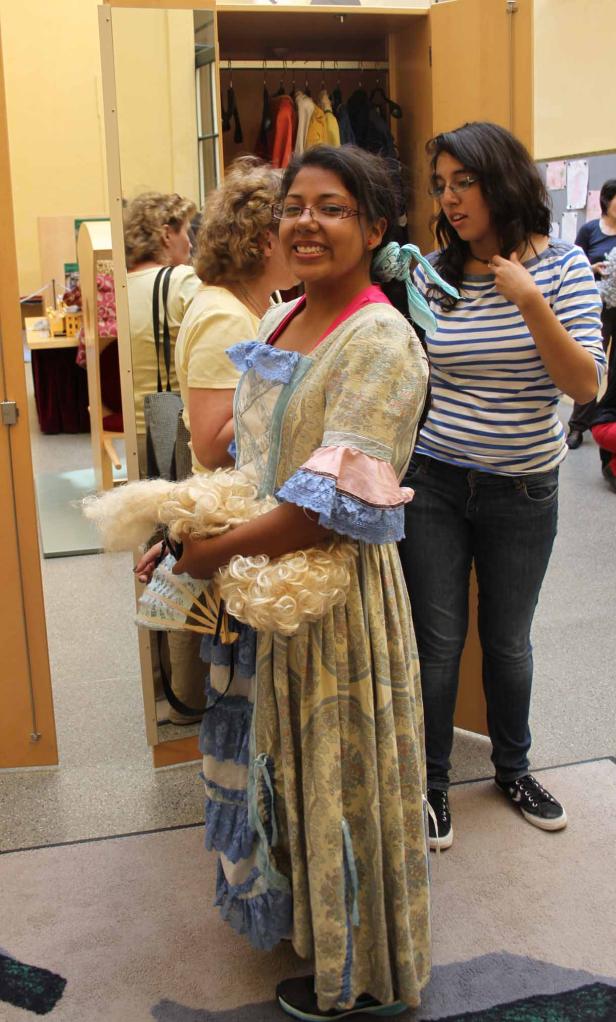 Eine junge Frau in einem historischen Kleid mit Perücke und Fächer.