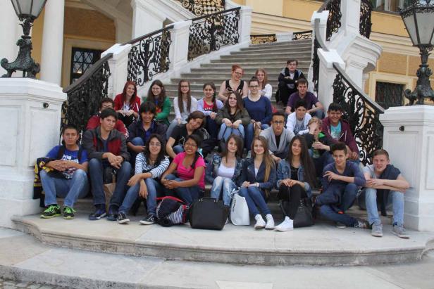 Eine Gruppe von Teenagern sitzt auf einer Treppe vor einem Gebäude.