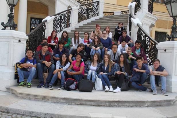 Eine Gruppe von Teenagern sitzt auf einer Treppe vor einem Gebäude.