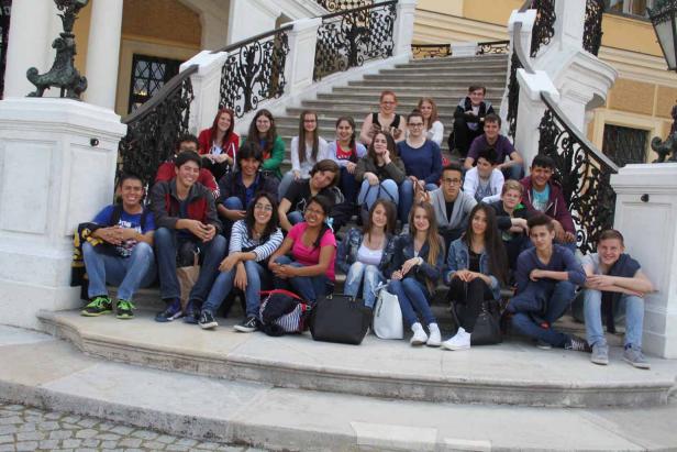 Eine Gruppe von Teenagern sitzt auf einer Treppe vor einem Gebäude.