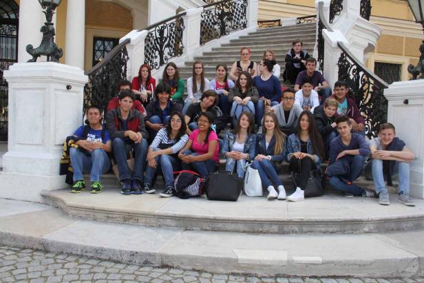 Eine Gruppe von Teenagern sitzt auf einer Treppe vor einem Gebäude.