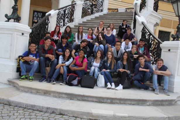 Eine Gruppe junger Leute sitzt auf den Stufen einer verzierten Treppe.