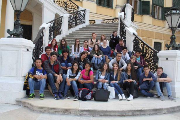 Eine Gruppe von Teenagern sitzt auf einer Treppe vor einem Gebäude.