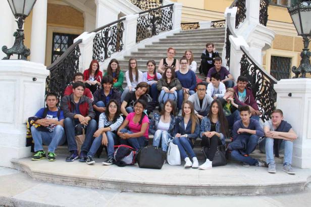 Eine Gruppe von Teenagern sitzt auf einer Treppe vor einem Gebäude.