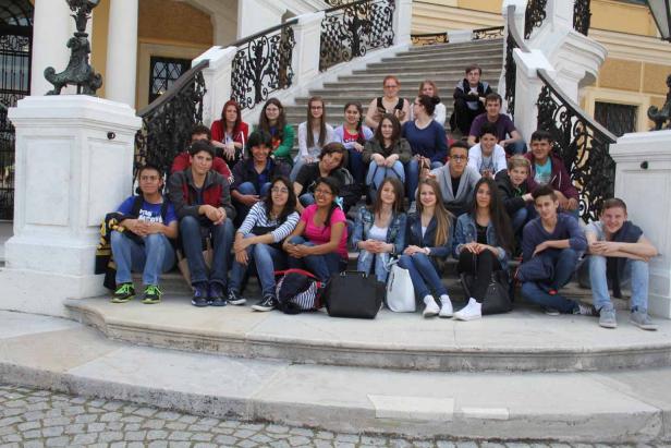 Eine Gruppe von Schülern sitzt auf einer Treppe vor einem Gebäude.
