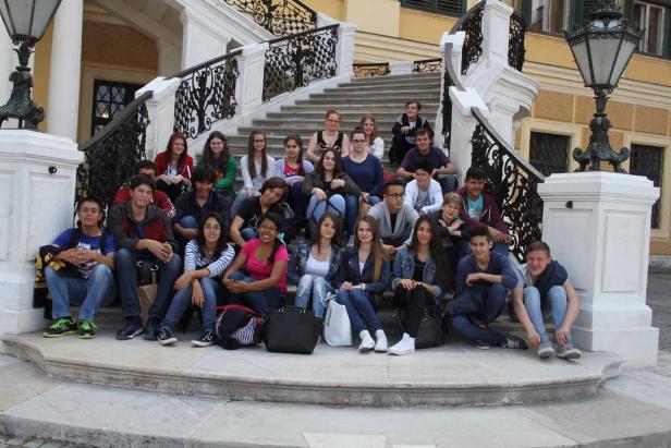 Eine Gruppe von Schülern sitzt auf einer Treppe vor einem Gebäude.