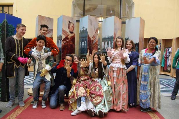 Eine Gruppe Jugendlicher in Kostümen posiert vor bemalten Kulissen.