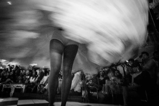 Eine Tänzerin wirbelt in einem Ballsaal vor Publikum.