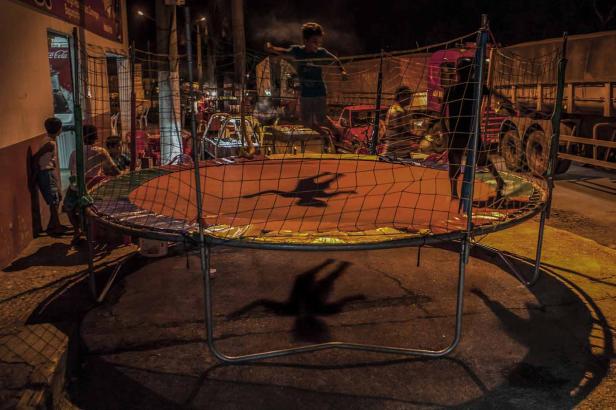 Ein Kind springt nachts auf einem Trampolin, während andere zusehen.