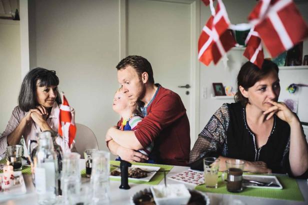 Eine Familie sitzt an einem Tisch, geschmückt mit dänischen Flaggen.