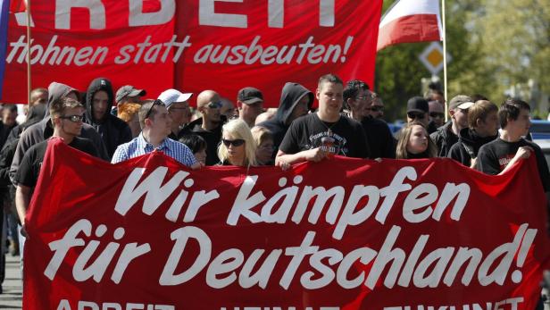 Eine Menschenmenge demonstriert mit einem roten Banner, auf dem „Wir kämpfen für Deutschland!“ steht.