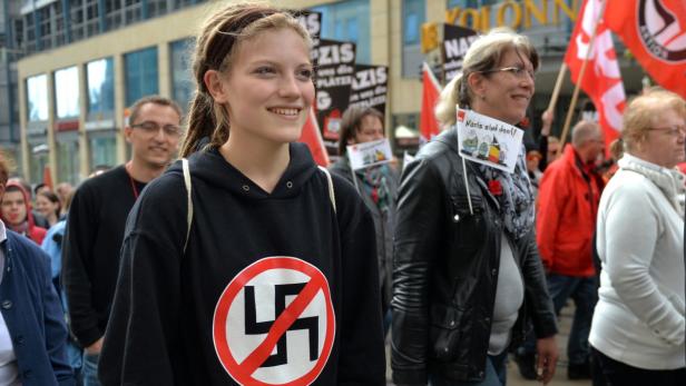 Eine junge Frau mit einem Antifa-Symbol auf ihrem Pullover nimmt an einer Demonstration teil.