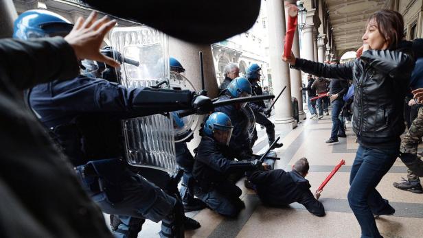 Bei einer Demonstration stehen sich Demonstranten und Polizisten mit Schutzschilden gegenüber.
