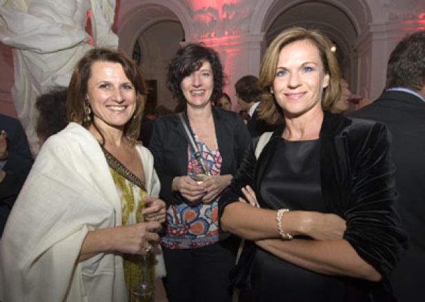 Drei Frauen posieren lächelnd auf einer Veranstaltung.