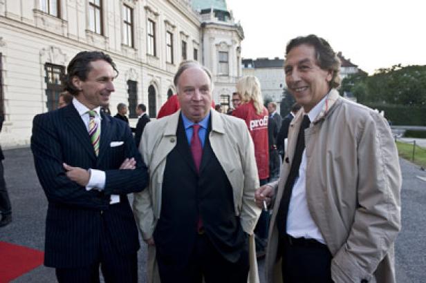 Drei Männer stehen vor einem Gebäude und unterhalten sich.