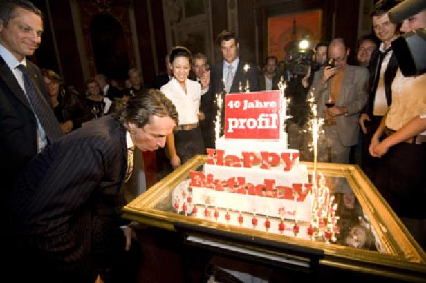 Ein Mann beugt sich vor, um die Kerzen auf einer Torte zum 40-jährigen Jubiläum von „Profil“ auszublasen.