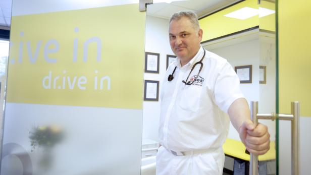 Ein Arzt mit Stethoskop öffnet die Tür zu einer „Live In Drive In“-Praxis.