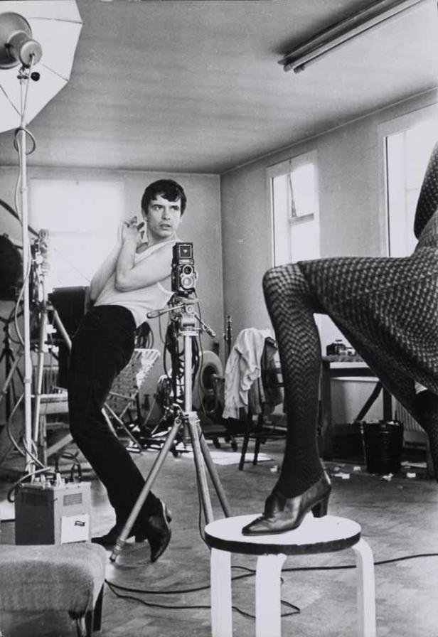 Ein Fotograf mit einer alten Kamera bei der Arbeit mit einem Model im Studio.