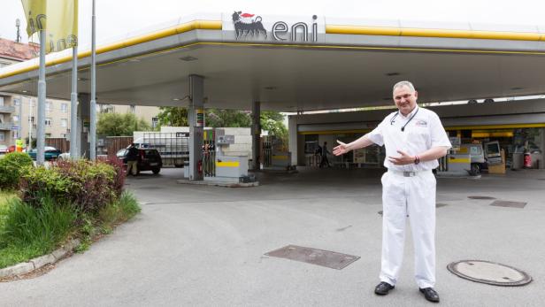 Ein Mann in weißer Kleidung steht vor einer Eni-Tankstelle.