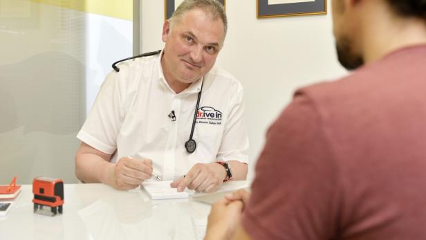 Ein Arzt mit Stethoskop schreibt etwas für einen Patienten.