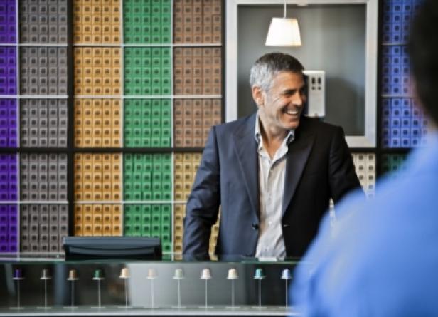 Nespresso/Episode 5/Making of/Mailand/George Clooney (c: nespresso) George Clooney lächelt vor einer Wand mit Nespresso-Kapseln.