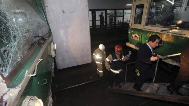 Nach einem Unfall inspizieren Rettungskräfte und ein Mann im Anzug einen beschädigten Zug.