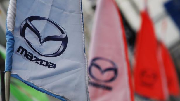 Mehrere Fahnen mit dem Mazda-Logo wehen im Wind.