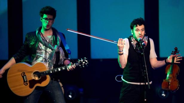 Zwei Musiker treten mit Gitarre und Geige auf einer Bühne auf.