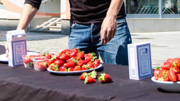 Ein Mann steht an einem Tisch mit Erdbeeren und Päckchen mit Zucker.