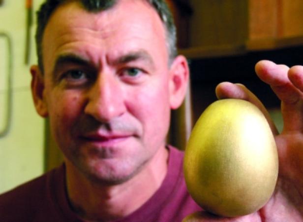 Ein Mann hält ein goldenes Ei in seiner Hand.