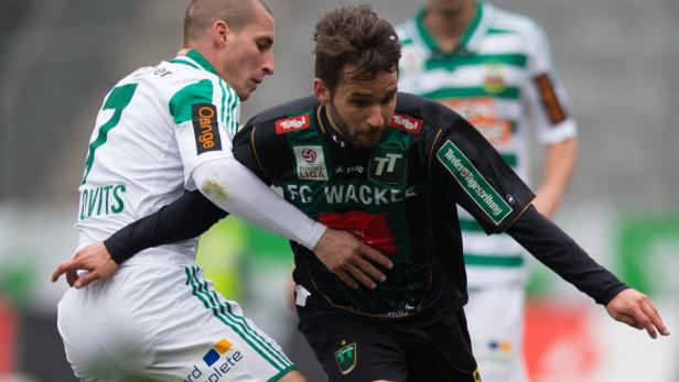 Zwei Fußballspieler kämpfen um den Ball während eines Spiels.