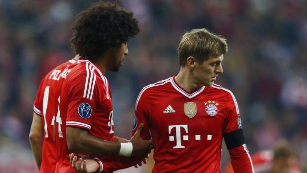 Zwei Fußballspieler des FC Bayern München in roten Trikots auf dem Spielfeld.