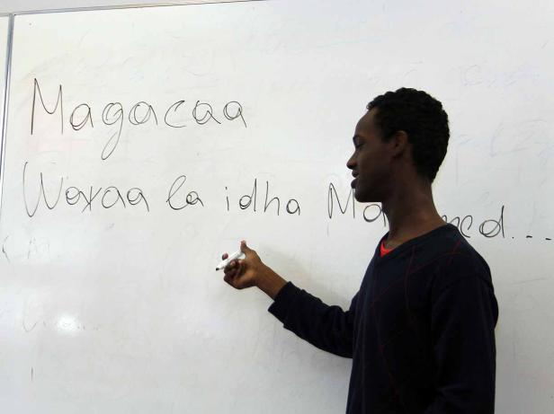 Ein junger Mann schreibt mit einem Stift auf eine weiße Tafel.