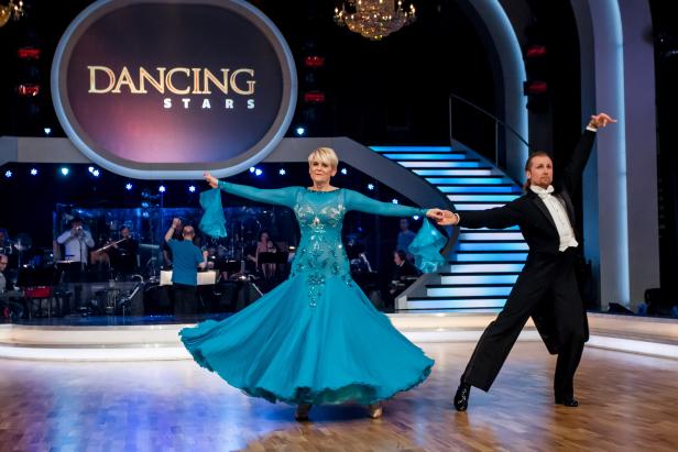 Eine Frau in einem türkisfarbenen Kleid tanzt mit einem Mann bei „Dancing Stars“.