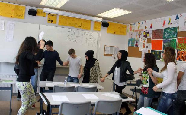 Eine Gruppe von Schülern hält Händchen in einem Klassenzimmer.