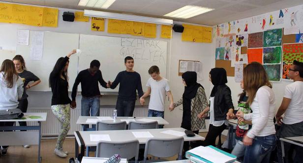 Eine Gruppe von Schülern hält Händchen in einem Klassenzimmer.