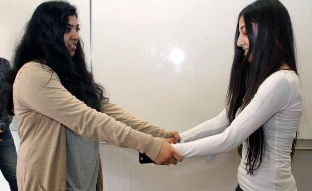 Zwei junge Frauen halten sich an den Händen.