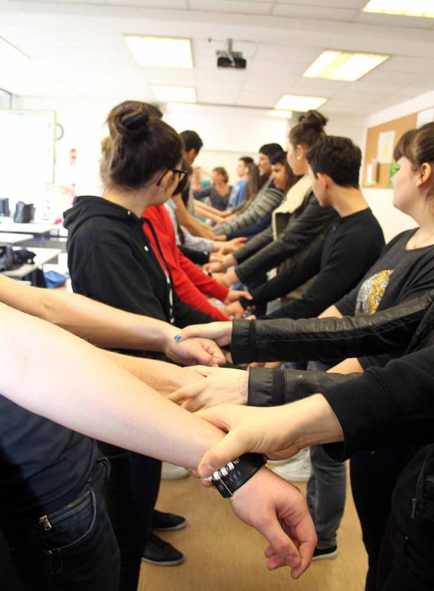 Eine Gruppe von Menschen hält sich in einem Raum an den Händen.